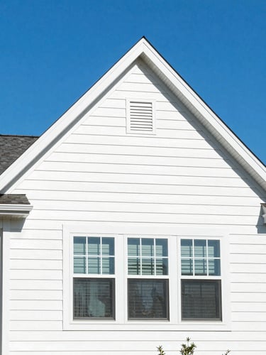 Bright mid-morning sunlight shining on a clean suburban house with immaculate vinyl siding, sharp architectural angles, highly saturated blue sky