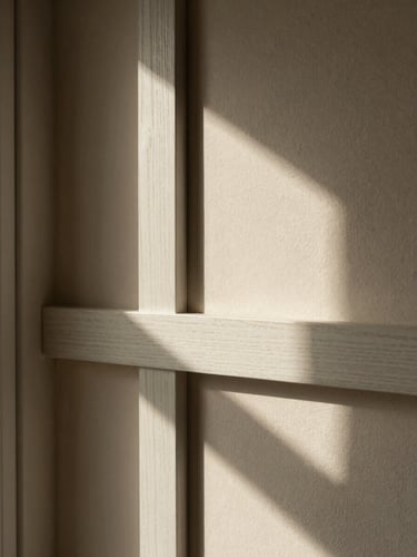 Macro architectural crop of a sunlit plaster wall, soft window side-light casting deep shadows onto a white oak joint, warm editorial photography, 50mm lens.