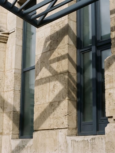 Abstract geometric shadows on a classic stone building facade, sharp angles, soft overcast daylight, 35mm photograph.