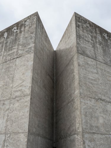 Symmetrical architectural elevation of a massive raw concrete structure under overcast daylight, sharp material joins, industrial scale.