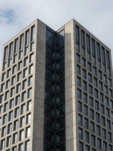 Symmetrical architectural elevation of a modern concrete and steel commercial tower under overcast morning light, clean lines, high contrast