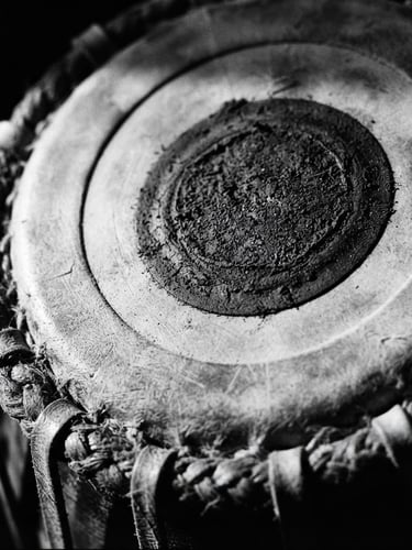 Extreme close-up macro shot of classical Indian Tabla leather head, dramatic side lighting casting deep shadows, high-contrast black and white, 35mm