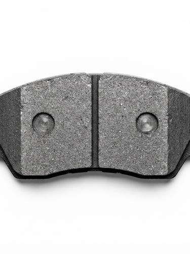 Macro studio product shot of a pristine metallic brake pad, top-down angle, high-contrast hard technical lighting, crisp white background, showing the chamfer and slot details.