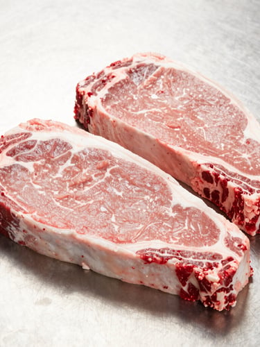 Bright commercial photography of fresh raw beef cuts arranged neatly on a clean stainless steel surface, crisp details, 50mm lens