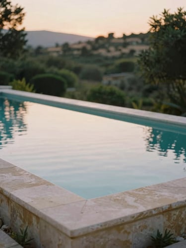 An empty stone infinity pool reflecting the soft dawn light, surrounded by lush Mediterranean greenery, quiet luxury atmosphere, shallow depth of field.
