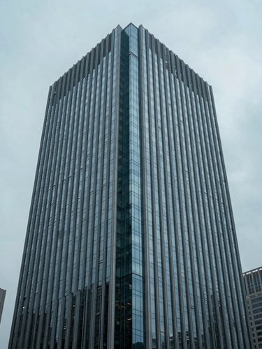 Cool editorial photography of sharp architectural lines of a modern financial district skyscraper reflecting a muted blue overcast sky, 35mm, sharp focus