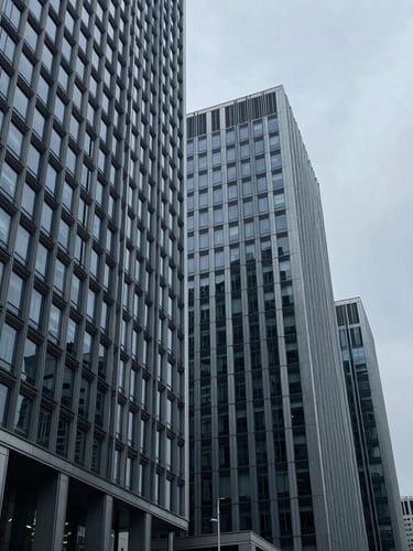 Wide-angle architectural lines of a modern financial district building facade, steel and glass structure under cool overcast daylight, muted blue and slate tones, sharp focus, 35mm.
