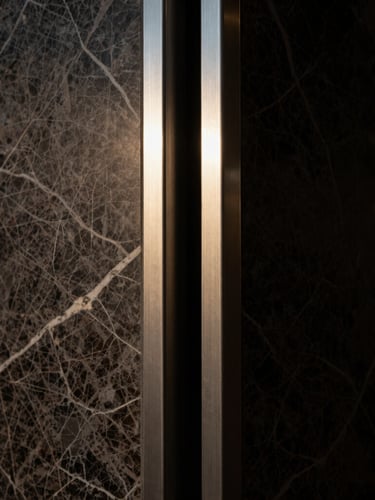 Extreme close-up of heavily veined dark marble meeting a perfectly aligned brushed steel frame, dramatic shadows, 35mm