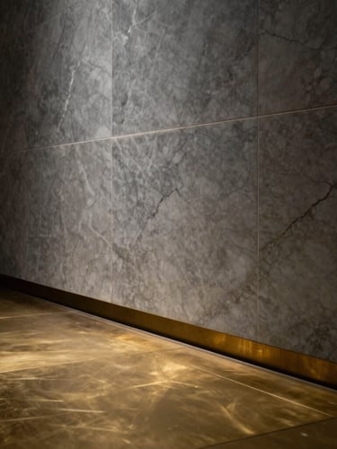 Dramatic low-key architectural photograph of a monolithic marble wall meeting a brushed brass floor inlay, razor-sharp alignment, deep shadows.