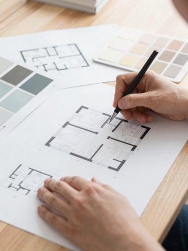 Close-up shot of hands organizing architectural floor plans and interior swatches on a wooden table, bright natural daylight, crisp clean colors, editorial style, shallow depth of field, 35mm lens.