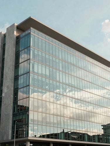 Wide architectural shot of a modern office building exterior in Bogotá, glass facade reflecting soft morning clouds, clean lines, 35mm corporate photography.