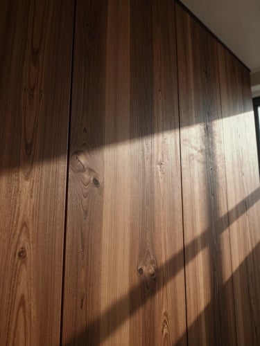 Low-angle natural mountain light hitting a textured walnut wood wall panel installation, casting deep soft shadows.