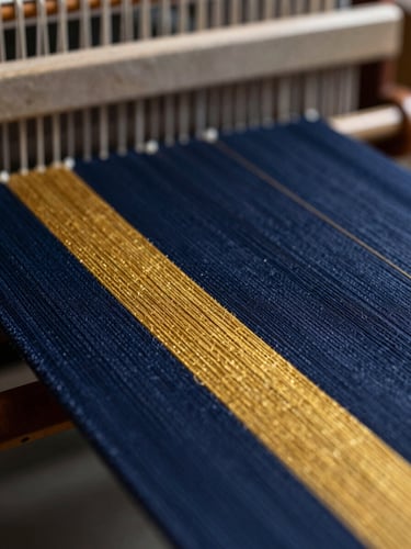 Macro close-up of premium navy and gold threads on an industrial loom, dramatic side lighting, shallow depth of field, 85mm lens