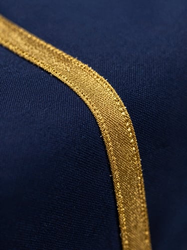 Macro close-up of dark navy blue premium cotton fabric weave, dramatic side studio lighting showing rich texture and gold-threaded selvage, shallow depth of field