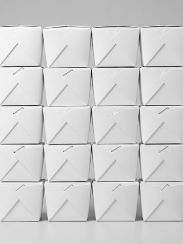 Straight-on product shot of neatly stacked durable white cardboard takeout boxes, bright high-key studio light, seamless light gray background, sharp focus, crisp details