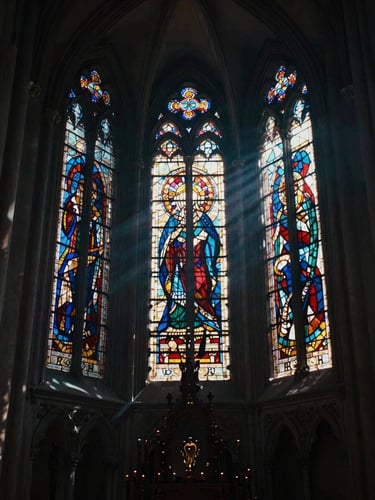 A vertical cinematic shot of a dark gothic cathedral interior, dramatic shafts of light through stained glass, moody haze, 9:16 aspect ratio.