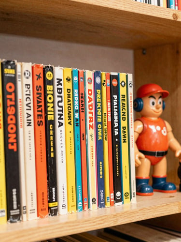 Vibrant editorial photography of neatly stacked vintage comic book spines and retro action figures on a wooden shelf, warm interior shop glow, 35mm lens