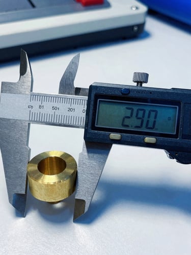 Macro photograph of a high-precision digital caliper measuring a machined brass component, clean industrial workspace, deep blue shadows, sharp focus