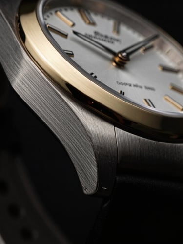 Extreme close-up of a luxury watch with brushed gold bezel, dramatic low-key studio lighting, deep shadows, high-contrast, 35mm