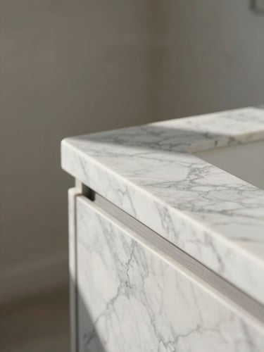 A tight, high-contrast portrait shot of natural morning daylight catching the clean, polished edge of a Carrara marble countertop against a soft neutral background.