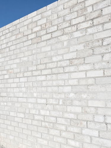 Close-up of a modern residential brick wall under construction, precise mortar lines, bright coastal daylight, professional engineering site visit