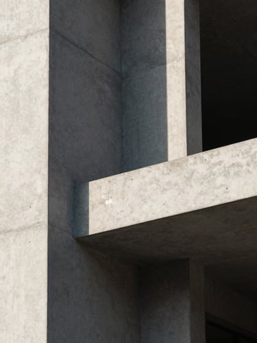 Extreme close-up of raw concrete architectural angles under harsh afternoon sunlight, casting deep geometric shadows across a clean minimalist facade.