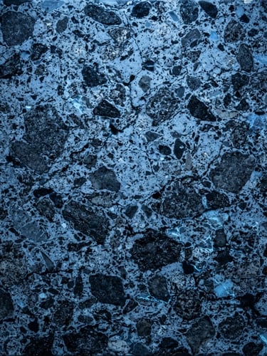 Extreme close-up of cured C80/95 high-strength concrete petrographic cross-section, industrial diagnostic blue light, high contrast