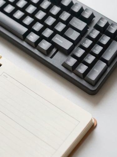 A top-down macro shot of a sleek mechanical keyboard next to a physical notebook showing a structured website copy outline, bright neutral morning light