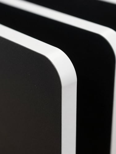 Extreme close-up of a rigid, ultra-matte step-and-repeat panel edge, showing crisp white borders and deep ink-black contrast.