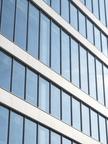 Sharp architectural photography of a modern glass office building, clean structural lines, bright high-key natural daylight, electric blue highlights, 35mm lens