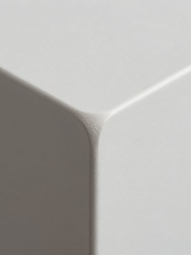 Extreme macro close-up of a perfectly curved solid surface corner joint, showing seamless monolithic flow, soft natural side lighting, pristine white matte texture.