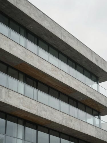 Architectural close-up of a modern concrete and glass facade, soft overcast daylight, muted slate tones, clean geometric lines, 35mm lens, shallow depth of field