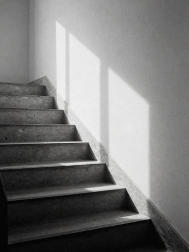 Minimalist desaturated photograph of a single concrete staircase in soft window light, high-contrast shadows, 35mm film grain style