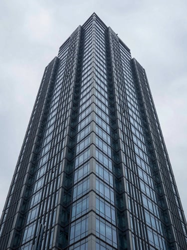 Low-angle architectural photography of a modern steel and glass skyscraper in Hyderabad, cool overcast daylight, deep blue and slate tones, sharp focus, 35mm