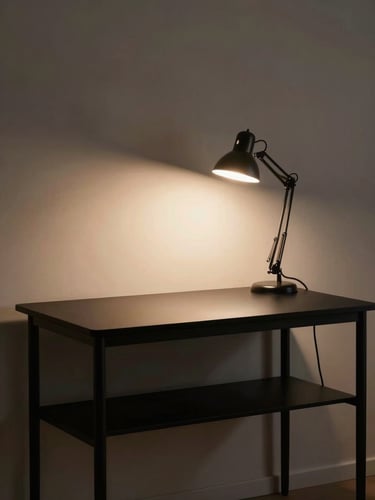 Wide environmental shot of an empty minimalist desk setup at night, single desk lamp casting warm light on a matte black desk shelf, clean cable management.