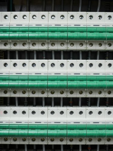 Macro shot of a perfectly organized distribution board, neat rows of circuit breakers with clean green and white wiring tags, sharp industrial technical lighting