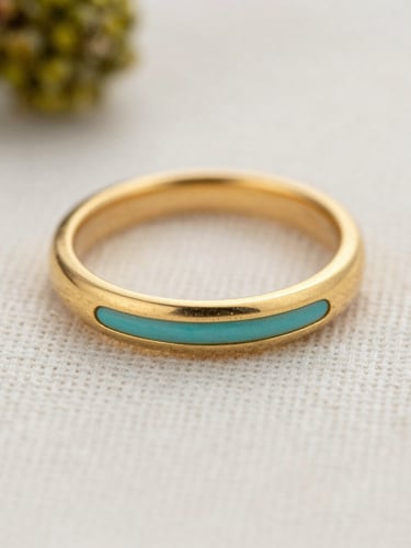 Extreme close-up macro shot of a matte gold ring with a subtle turquoise accent resting on textured off-white linen, soft diffused daylight, shallow depth of field