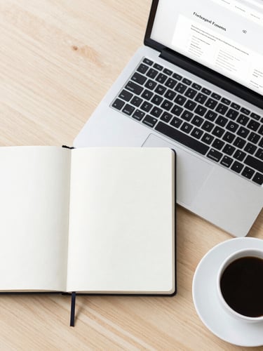 A clean modern overhead flat-lay of an open notebook, a sleek laptop showing a clean website outline, and a cup of black coffee on a light wooden desk, bright natural daylight