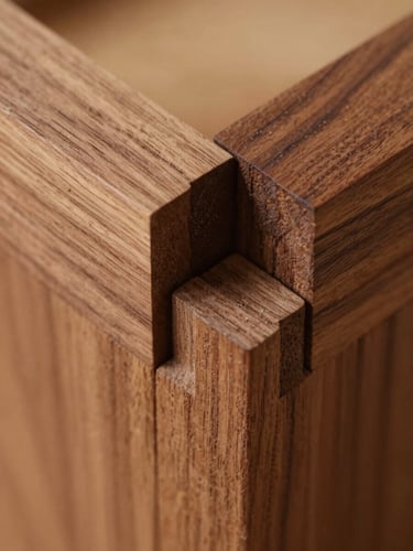Macro detail shot of interlocking mortise and tenon joint in seasoned walnut wood, warm tactile photography, natural workshop side-lighting, rich organic wood tones, sharp details, shallow depth of field