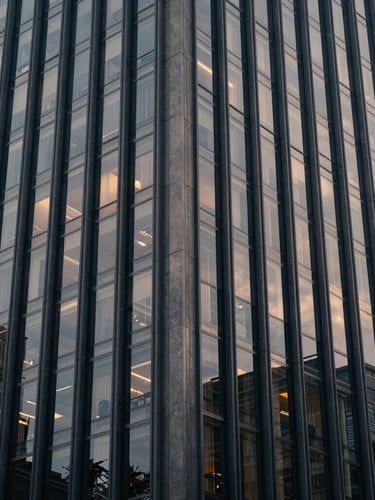 Architectural wide shot of a modern financial capital skyscraper facade, soft diffused window light, muted navy tones, 35mm.