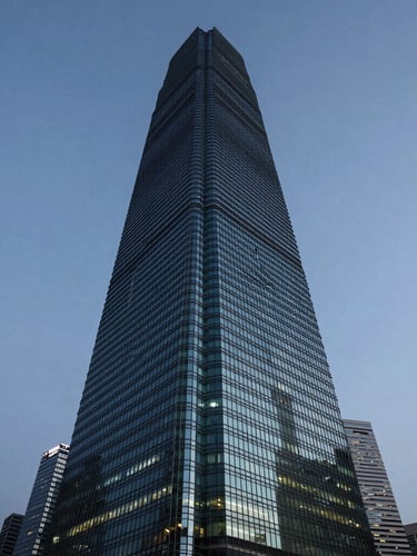 Wide-angle architectural crop of the Hong Kong International Finance Centre towering into a cool blue-hour sky, deep obsidian shadows and sharp jade reflections in the glass facade