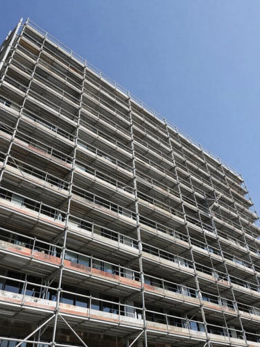 Wide-angle architectural lens shot of perfectly aligned steel scaffolding rising up a modern Los Angeles commercial building under bright Southern California sunlight, crisp shadows.