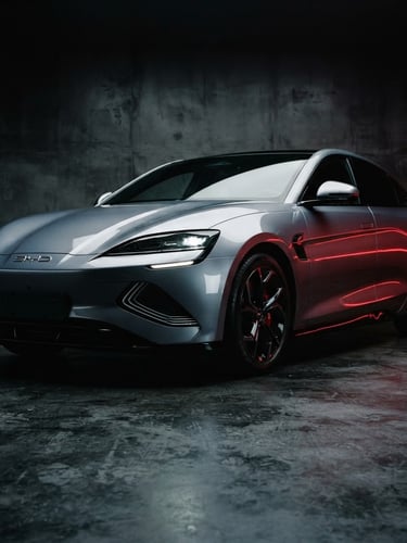 Sleek metallic grey BYD Seal electric sedan parked in a high-contrast minimalist concrete studio, cinematic low-angle shot, dramatic red neon reflections, sharp metallic curves, 35mm photography