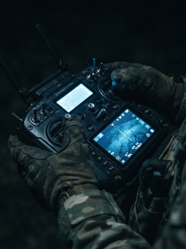 Close-up of hands holding a tactical drone controller, cool blue screen glow reflecting on fingers, high-tech military hardware, deep shadows, moody lighting