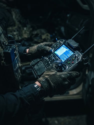 Close-up of hands holding a military UAV controller, cool blue screen glow reflecting on fingers, dark tactical background, sharp focus, 35mm lens