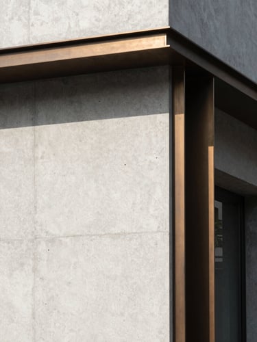 Minimalist architectural detail with high-contrast shadows, clean concrete and bronze accents, natural side lighting