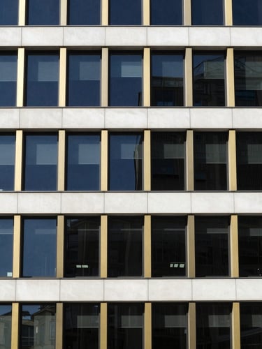 High-contrast architectural detail of a modern office building facade, clean lines, deep navy and gold accents, bright natural daylight, minimalist composition, 35mm