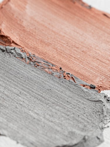 Macro close-up of textured paint strokes on heavy watercolor paper, showcasing layered terracotta and ash gray pigments under soft side-lighting