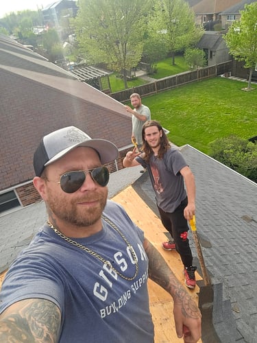 Professional roofing contractors removing old asphalt shingles during a residential roof replacement project.