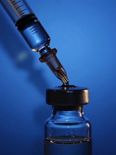 Macro shot of liquid transferring through a precise glass syringe into a minimalist vial, royal blue studio background, deep shadows, high contrast.